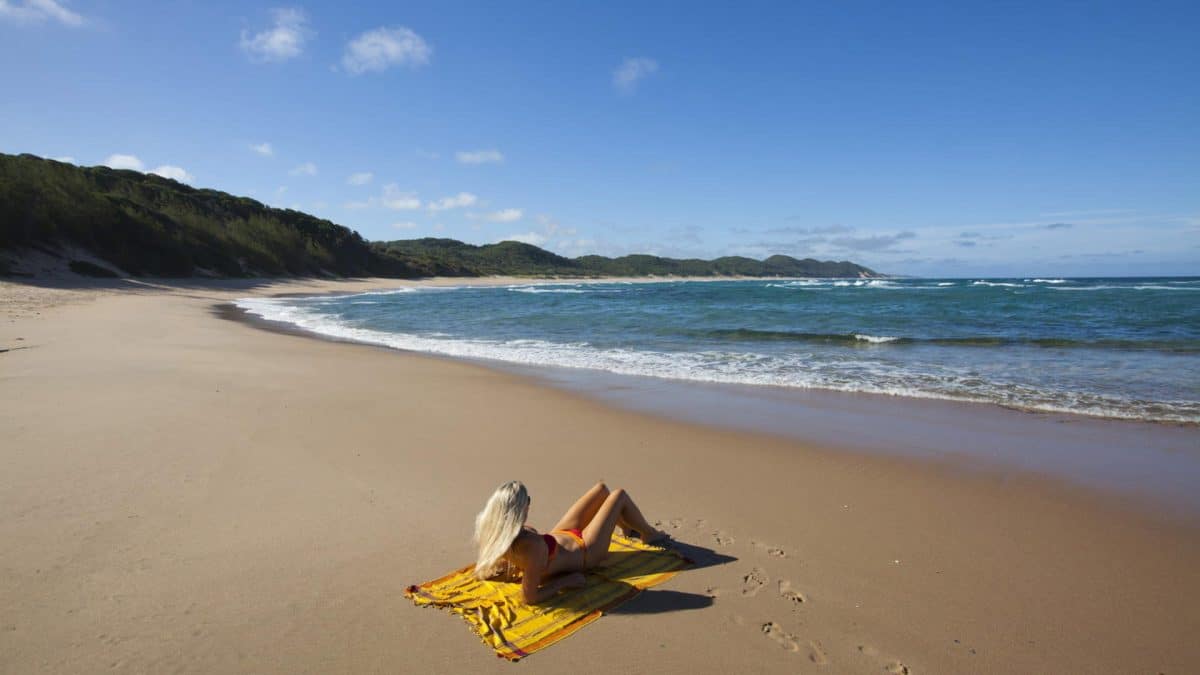 una ragazza si abbronza al sole dell'elephant coast sulla spiaggia di cape vidal